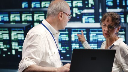 Poster - older colleagues looking around innovative server farm, preparing to start comission on malfunctioni