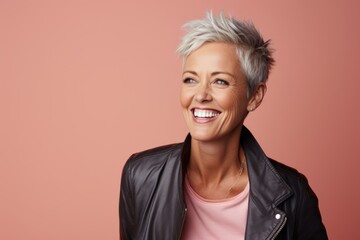 Wall Mural - Mature woman with short grey hair. Attractive mature woman looking at camera and smiling while standing against pink background