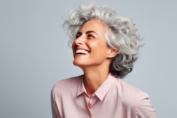 Portrait of a happy senior woman with grey hair on grey background