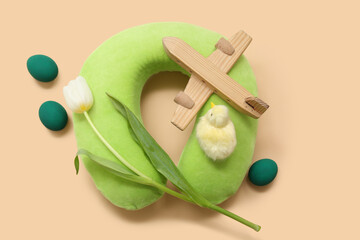 Sticker - Travel pillow with toy plane, tulip and Easter decor on beige background. Holiday trip composition