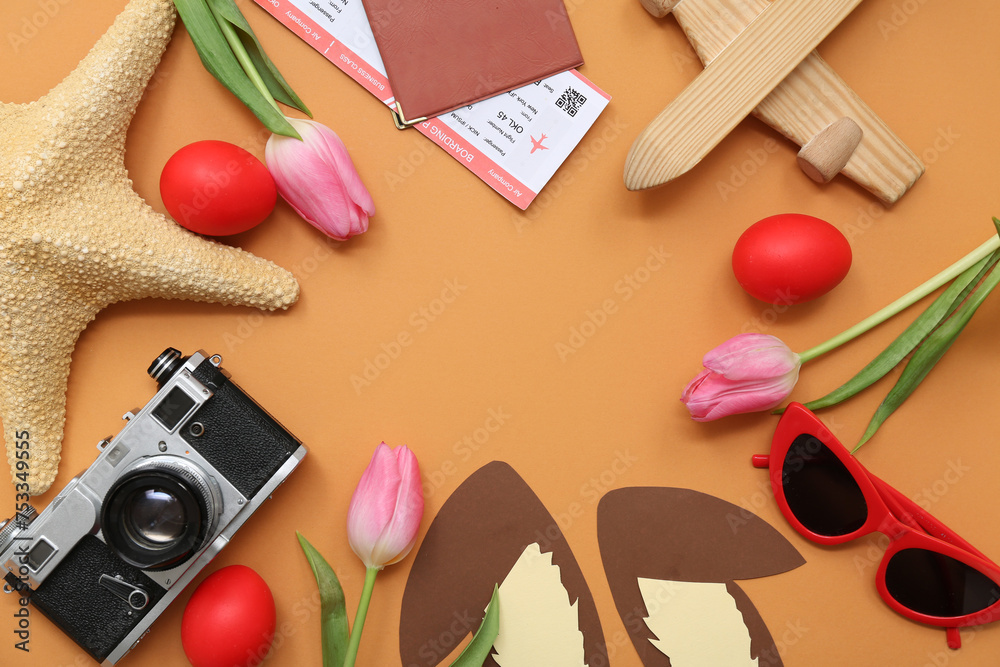 Frame made of trip items with Easter decor and tulips on orange background. Holiday travel composition