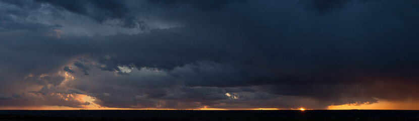 Wall Mural - Landscape at sunset. A thunderstorm is approaching the village. Tragic gloomy sky. Panorama.