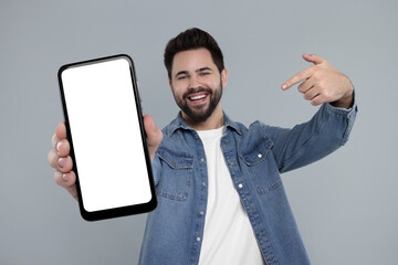 Sticker - Happy man holding smartphone with empty screen on grey background