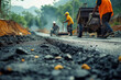 Road construction, tarmac laying works at a road construction site, hot asphalt gravel leveled by workers, and road surface repair..