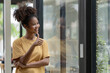 © Songsak C - Young pretty African American standing and arms crossed near a window.