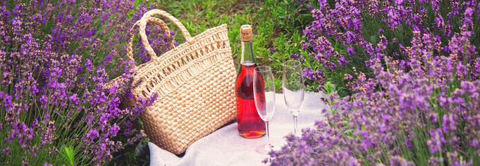 Wall Mural - two glasses and pink wine in a lavender field. Violet flowers on the background