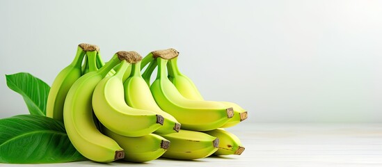 Fototapete - Vibrant Bunch of Fresh Bananas with Tropical Green Leaves on a Clean White Table