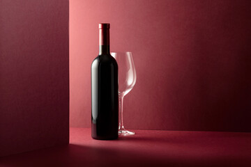 Wall Mural - Bottle and glass of red wine on a red background.