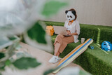 Fototapeta Tęcza - Businesswoman in mask of panda working in the lounge zone in office