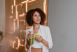 Fototapeta Tęcza - Woman using smartphone drinking green smoothie with bamboo straw in the office