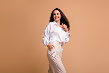 Wall Mural - Photo of cute good mood lady dressed white shirt walking looking empty space isolated beige color background