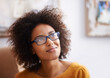 © Mapodile/peopleimages.com - Thinking, calm and relax woman in home lounge, smile and eyewear for happy lady. Apartment, dreaming or wondering with hope for African women person, ideas and possibilities in living room of house