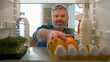 © Yuliia - Point of view POV from inside refrigerator fridge middle-aged Caucasian man buyer customer unpack food delivery shopping bag with healthy meal in kitchen unpacking paper package vegetables products