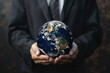 man dressed in black suit and white shirt with tie holding big planet earth in his hands