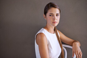 Wall Mural - Woman, portrait and serious in chair in studio and relax by grey background for rest. French designer, glow and face in formal fashion or elegant and creative career with confidence in mock up