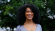 © Marco - One happy Brazilian young black woman smiling and laughing while posing for camera outside in city street. Curly hair African American descent person authentic feeling joy