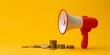 Red megaphone and stack of coins on yellow background, marketing investment concept