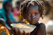 Global efforts to reduce poverty and hunger. A toddler is holding a bowl of staple food in an african village on a sunny day. Young african girl is pictured with a bowl of food on a market with other 