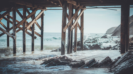 Poster - Ocean view with pier posts, water, and rocks below