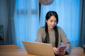 Canvas Print - Woman use notebook computer with use of cellphone at home