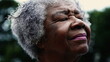 © Marco - Grateful Senior African American woman closing eyes in Spiritual contemplation standing outside, close-up face of one black elderly gray hair lady in 80s feeling presence of GOD