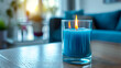 A bold electric blue candle standing tall in a simple glass holder, creating a striking focal point in the room.