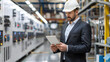 © Kolapatha - Focused engineer wearing a hard hat using a tablet to monitor machinery in a modern industrial factory.