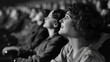 © Pillow Productions - A smiling woman is depicted in a crowded 1930s movie theater, thoroughly enjoying a film, as shown in a black and white photograph