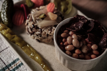 traditional turkish white beans stew with bacon, boiled rice and salted marinade vegetables, cucumbers, green tomatoes, carrot, pepper, served ready to eat kuru fasulye