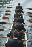 Fototapeta Uliczki - Group of businessmen in suits row oars in a boat on the river at competition, concept of perfect candidate and team building work with colleagues.