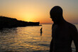 © Luciano Spinelli/Stocksy - Silhouette of a man at the beach looking down and woman inside water