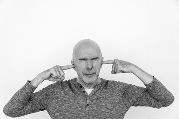 Mature man with his fingers in his ears and eyes closed. Black and white.