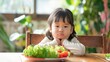 A little Asian girl looking disappointed as she refuses to eat her salad and vegetables, showcasing picky eating behavior at mealtime