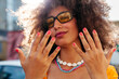 © Viktor Solomin/Stocksy - Young curly hair woman showing fingers on street