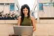 © Ezequiel Giménez/Stocksy - Happy, smiling young student with laptop computer in open air