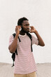 © Ezequiel Giménez/Stocksy - Stylish black guy putting on headphones on street