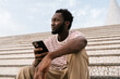 © Ezequiel Giménez/Stocksy - Black guy sitting on staircase with mobile phone