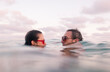 © Ibai Acevedo/Stocksy - Couple inside the sea with vintage sunglasses
