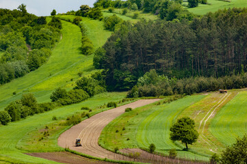 Spring farmland in the hills. Roztocze. Poland. Field work in herbal fields.