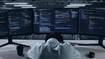 Back View Of Tired Asian Man Developer Sleeping While Write Code With Multiple Computer Screens In Data Center