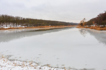 Wall Mural - Ice is melting on the pond. Background with selective focus and copy space