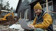 © Irina.Pl - Construction worker in beanie using laptop on site with machinery behind. Smiling builder manages project plans online amidst renovation. Construction site supervisor checks work progress on computer.