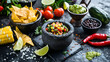 A sample of traditional Mexican cuisine with freshly made guacamole served in rustic stone molcajetes, accompanied by crunchy tortilla chips, tomatoes, chili peppers, black beans, corn and lime wedges