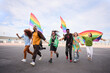 © CarlosBarquero - A group of LGBT people is leisurely walking down the street in the gay pride day parade holding colorful rainbow flags, enjoying a fun, friendship and happy event. Diverse men and women run together