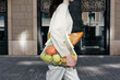 © Sergey Narevskih/Stocksy - Crop woman walking along street with mesh bag of groceries