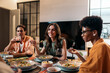 © Santi Nuñez/Stocksy - Diverse Friends Having Dinner at home While chatting