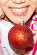 © Danil Nevsky/Stocksy - Crop woman with bauble in teeth