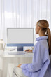 © Artem Podrez/Stocksy - a woman works at a computer with a white screen in a modern office