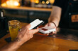 © Pixel Stories/Stocksy - Tap to pay mobile phone payment transaction/purchase at bar