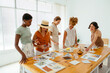 © BONNINSTUDIO/Stocksy - Group of diverse colleagues discussing project in workshop